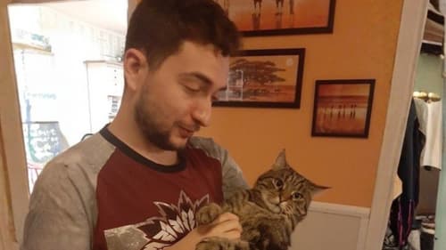 Roman Sterlingov holding a tabby cat at home
